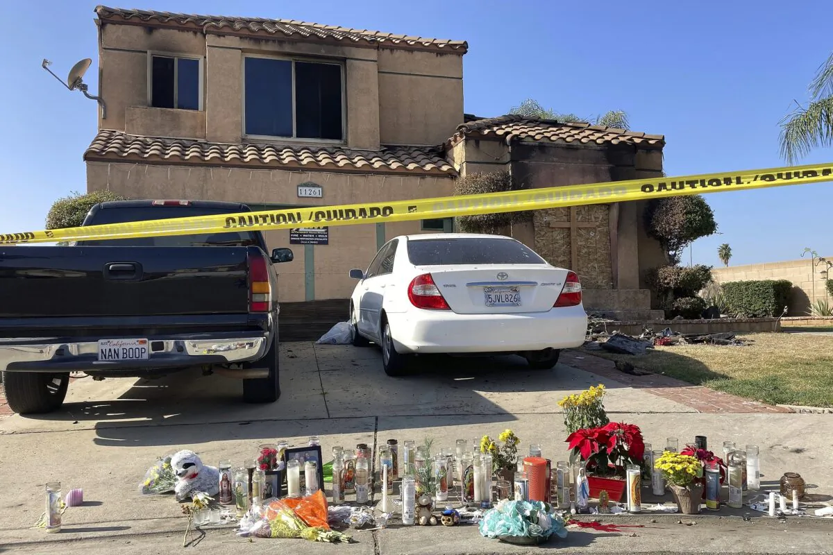 Dozens of candles sit placed on the sidewalk along with bouquets of flowers and stuffed animals outside a charred home in Riverside, Calif., on Nov. 30, 2022. (Amy Taxin/AP Photo)
