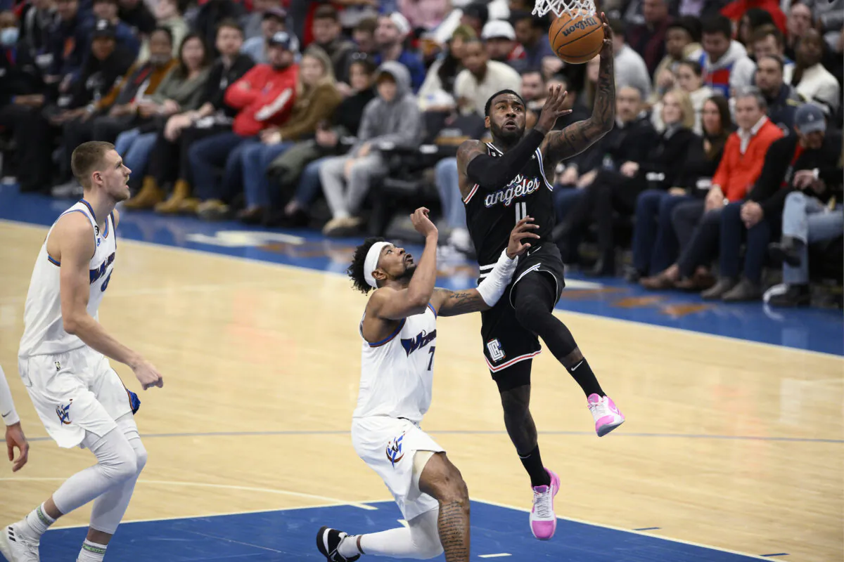 Los Angeles Clippers guard John Wall (11) goes to the basket against Washington Wizards guard Jordan Goodwin (7) and center Kristaps Porzingis, left, during the first half of an NBA basketball game, in Washington, on Dec. 10, 2022. (Nick Wass/AP Photo)
