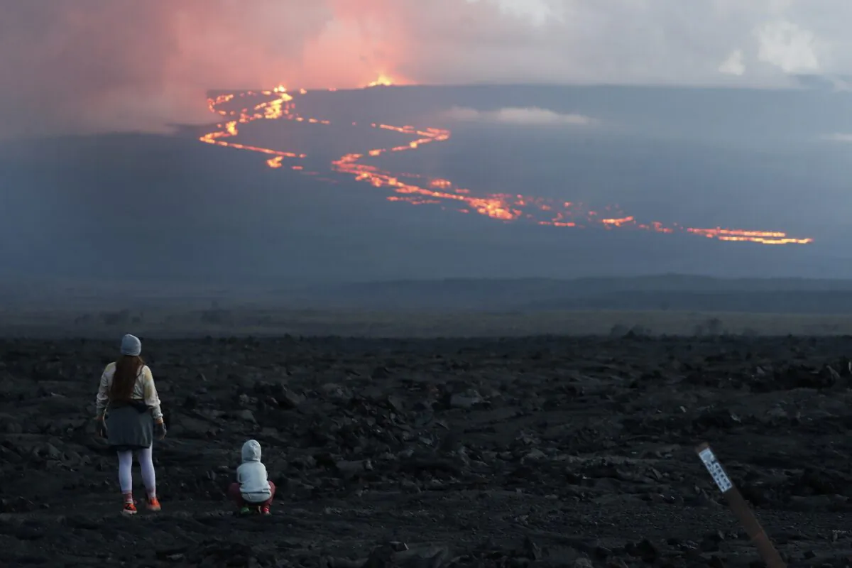 Spectators watch the lava flow down the mountain from the Mauna Loa eruption near Hilo, Hawaii, on Nov. 29, 2022. (Marco Garcia/AP Photo)
