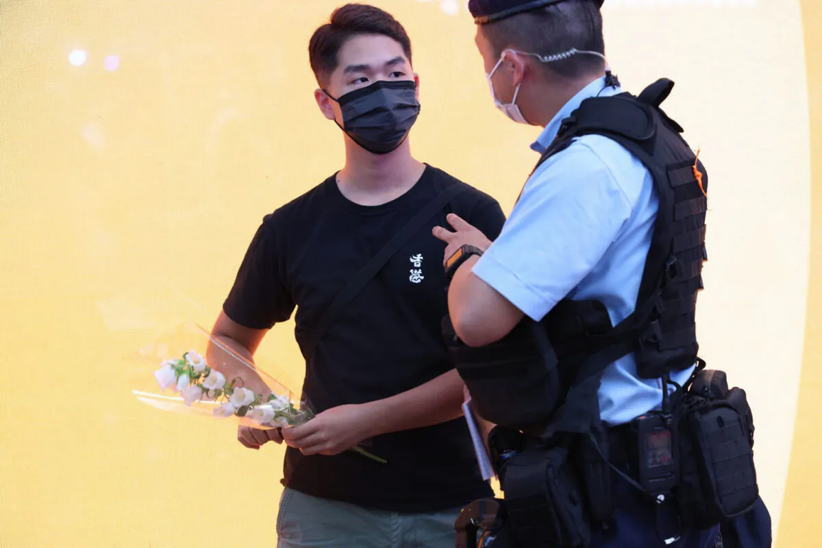 Lots of citizens held white flowers, dressed in black to mourn Leung on July 2, 2022. The photo shows a man holding a white flower, he was intercepted by the police. (Li Chen/The Epoch Times)