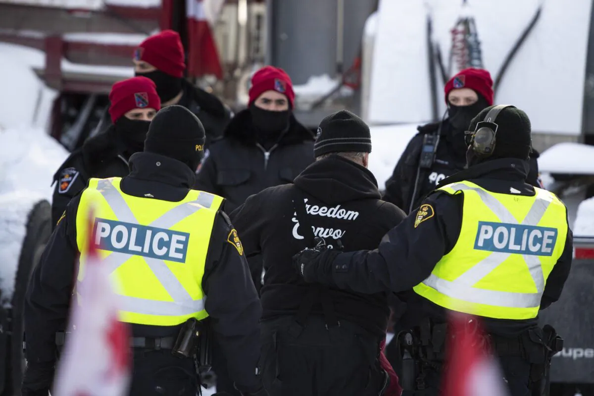 A person is led away after leaving his truck as police aim to end an ongoing protest against COVID-19 measures that has grown into a broader anti-government protest, on its 22nd day, in Ottawa, on Feb. 18, 2022. (The Canadian Press/Justin Tang)
