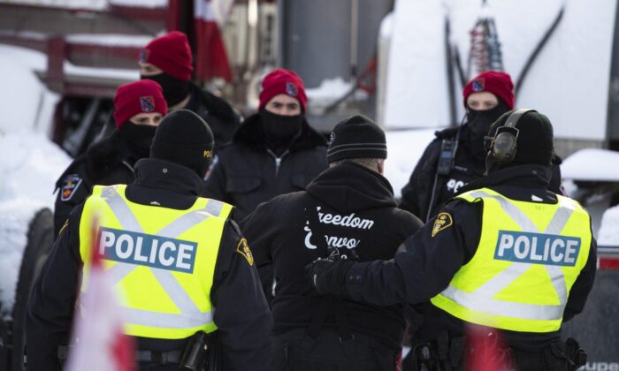 2022 年 2 月 18 日，在渥太华举行的第 22 天，警察旨在结束针对 COVID-19 措施的持续抗议，该抗议活动已发展成为更广泛的反政府抗议活动，一名男子在离开卡车后被带走。（加新社/贾斯汀唐）
