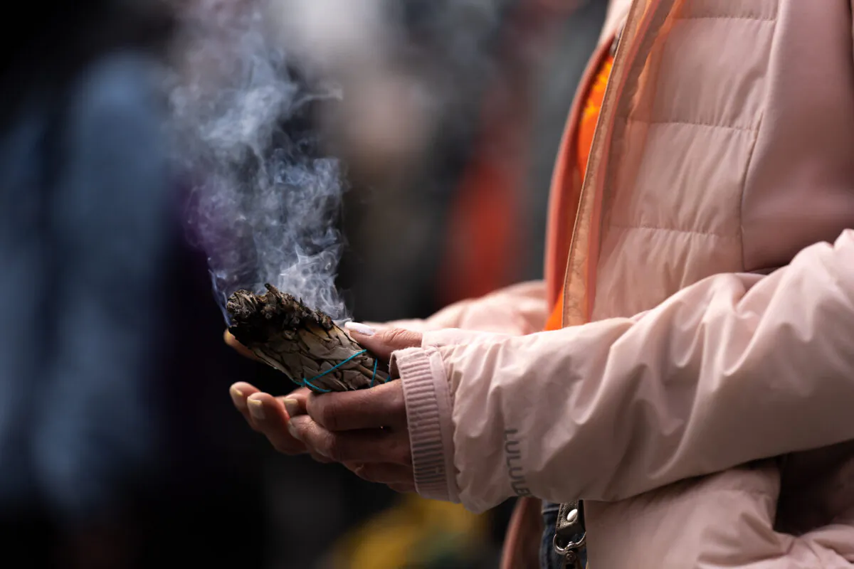 A file photo of a woman holding an Indigenous smudge stick at Yonge and Dundas Square in Toronto on April 18, 2022. (Yader Guzman/The Canadian Press)