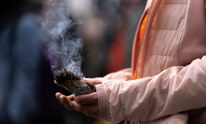 2022 年 4 月 18 日，一名妇女在多伦多央街和登打士广场手持土着涂抹棒的档案照片。（Yader Guzman/加拿大出版社）