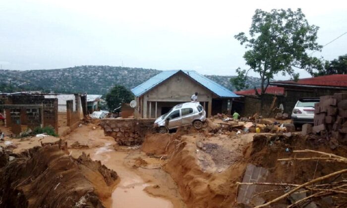 2022 年 12 月 13 日，在刚果民主共和国金沙萨郊区，大雨引发洪水和山体滑坡后，人们看到一辆汽车。（斯金格/路透社）