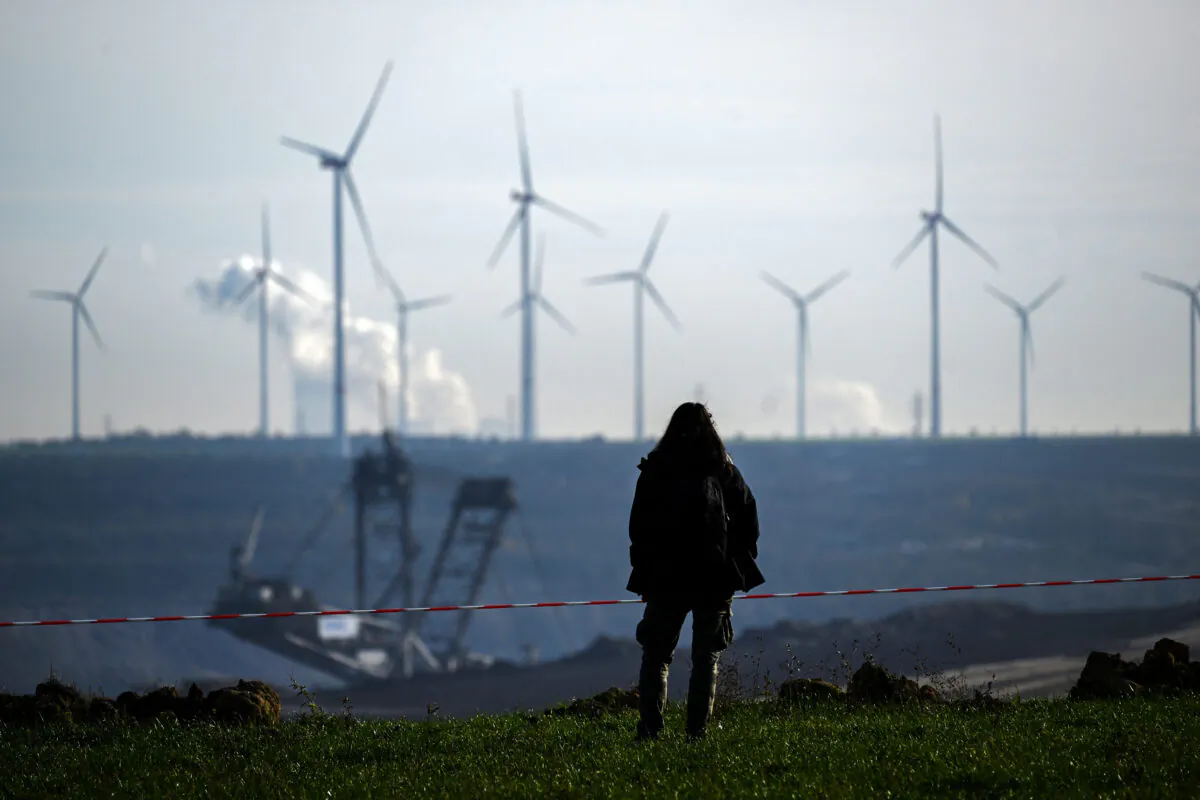 A woman stands on the edge of the Garzweiler lignite open cast mine near Luetzerath, western Germany, on Nov. 12, 2022, as in background can be seen wind engines. (Ina Fassbender/AFP via Getty Images)