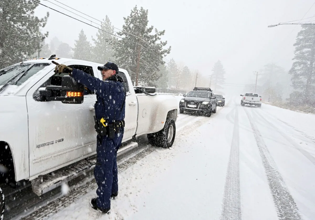 California Highway Patrol officer Mike Eshleman instructs a driver he may continue on Highway 2 in his 4-wheel drive vehicle as heavy snow falls near Wrightwood, Calif., on Dec. 12, 2022. (Will Lester/The Orange County Register via AP)