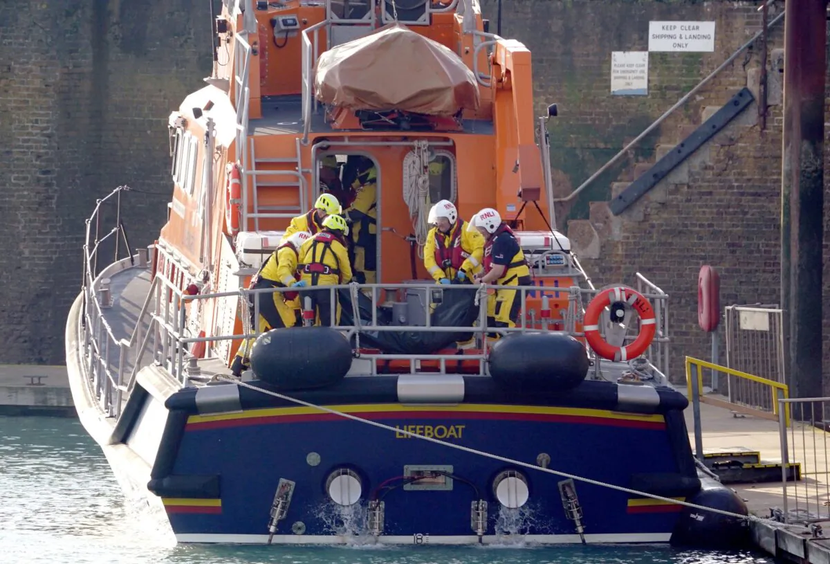 Members of the Dover lifeboat place a body bag on a stretcher after returning to the Port of Dover following a large search and rescue operation launched in the English Channel off the coast of Dungeness, in Kent, southeast England, on Dec. 14, 2022. (Gareth Fuller/PA Media)