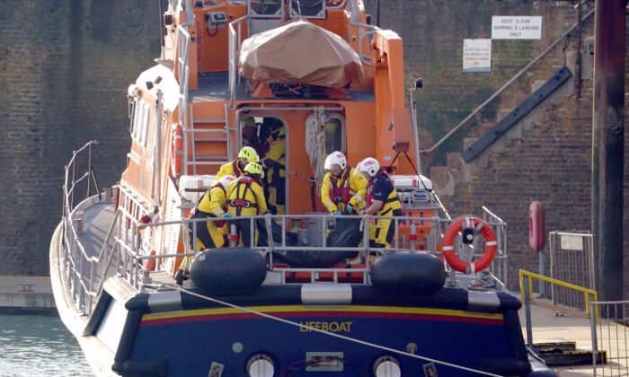 2022 年 12 月 14 日，在英格兰东南部肯特郡邓杰内斯海岸附近的英吉利海峡展开大规模搜救行动后，多佛救生艇的成员在返回多佛港后将尸体袋放在担架上。 （加雷斯·富勒/PA Media）
