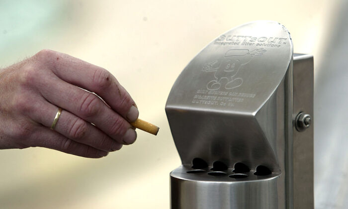 2004 年 12 月 10 日，在新西兰奥克兰，作为 ACC 计划的一部分，一个人向吸烟者展示了新的垃圾桶。（Michael Bradley/Getty Images）