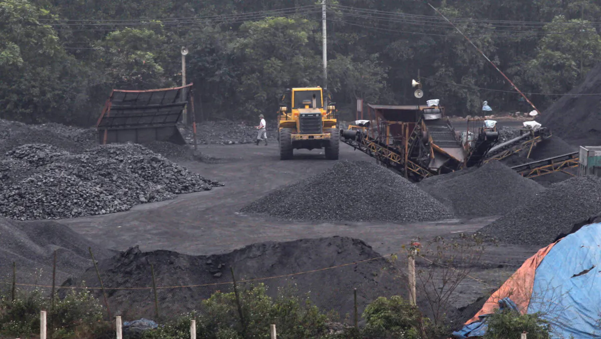 Workers walk near an excavator loading coal onto a truck at a coal port in Hanoi, Vietnam, on Feb. 23, 2012. (Kham/Reuters)