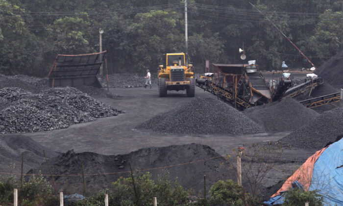 2012 年 2 月 23 日，在越南河内的一个煤炭港口，工人们走近一台正在将煤炭装载到卡车上的挖掘机。（Kham/路透社）