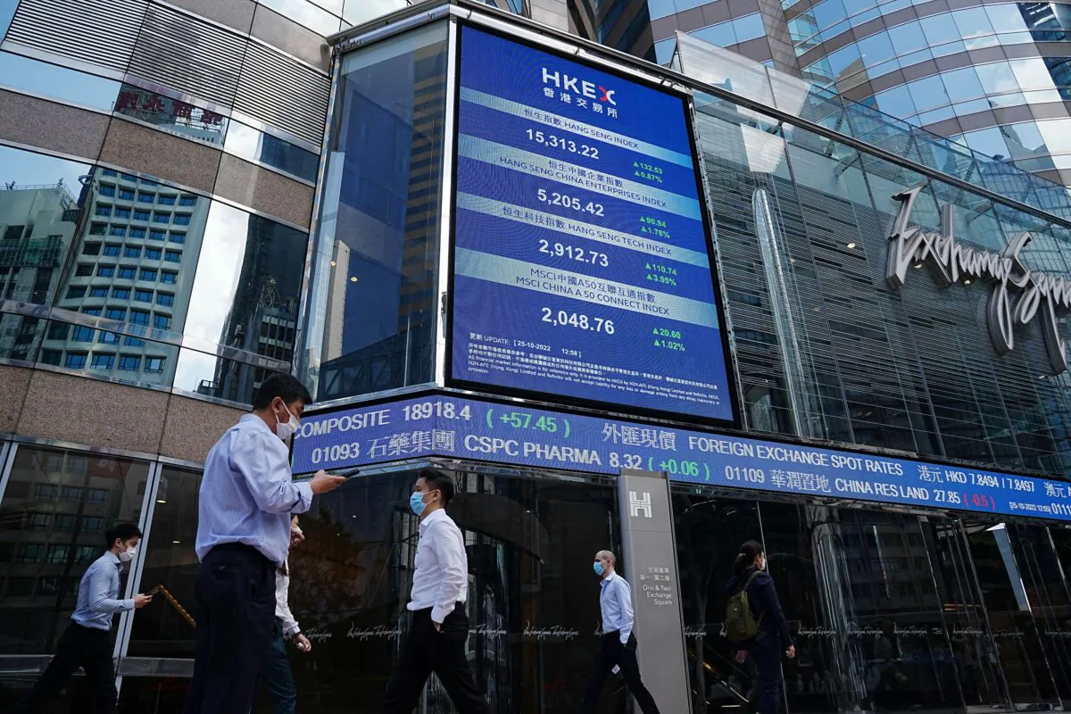 People walk past a screen displaying the Hang Seng stock index at Central district, in Hong Kong, China, on Oct. 25, 2022. (Lam Yik/Reuters)