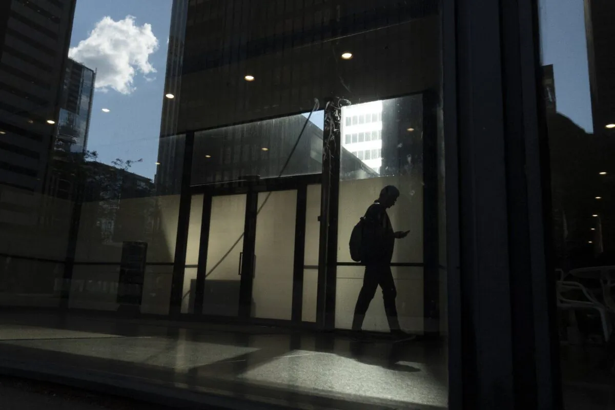 A man walks though a downtown Toronto office building with other buildings reflected in a window in this June 11, 2019 photo. (The Canadian Press/Graeme Roy)
