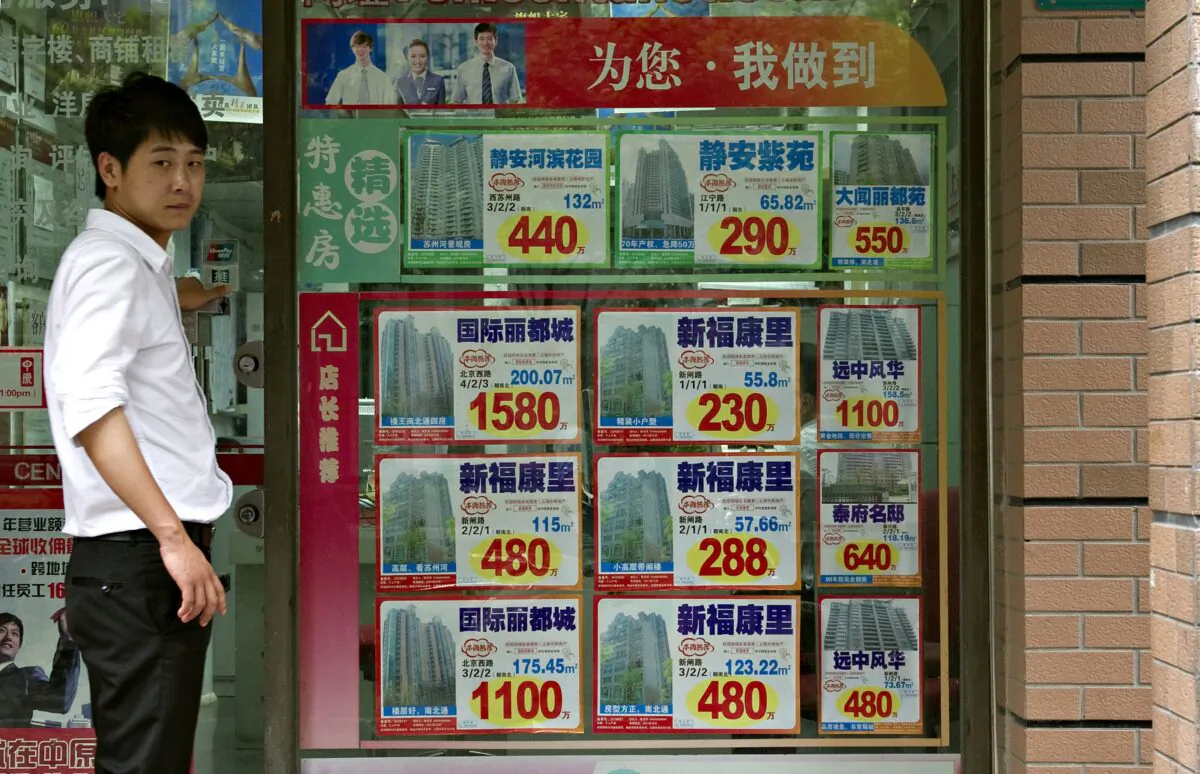A Chinese employee of a real estate agency looks on next to a display of properties listed for sale in Shanghai, on July 4, 2011. (Philippe Lopez / AFP via Getty Images)