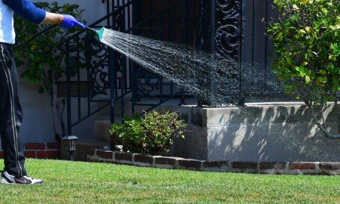 2022 年 4 月 27 日，一名男子在加利福尼亚州阿罕布拉为他的草坪浇水。（Frederic J. Brown/AFP via Getty Images）