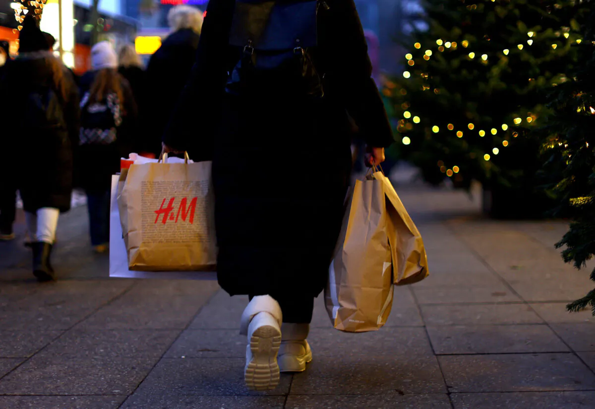 A woman carries a shopping bag branded with the fashion chain H&M as she walks along Kurfuerstendamm shopping street looking for bargains on the second weekend of advent in Berlin on Dec. 3, 2022. (Lisi Niesner/Reuters)