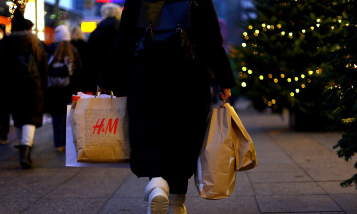 2022 年 12 月 3 日，在柏林降临节的第二个周末，一位女士提着印有时尚连锁店 H&M 品牌的购物袋走在 Kurfuerstendamm 购物街上寻找便宜货。（Lisi Niesner/路透社）