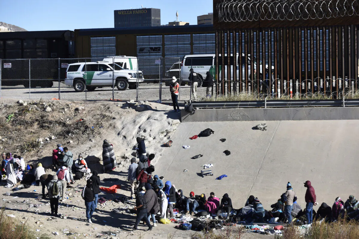 Illegal immigrants wait to cross the U.S.-Mexico border from Ciudad Juárez, next to U.S. Border Patrol vehicles in El Paso, Texas, on Dec. 14, 2022. (AP Photo/Christian Chavez)