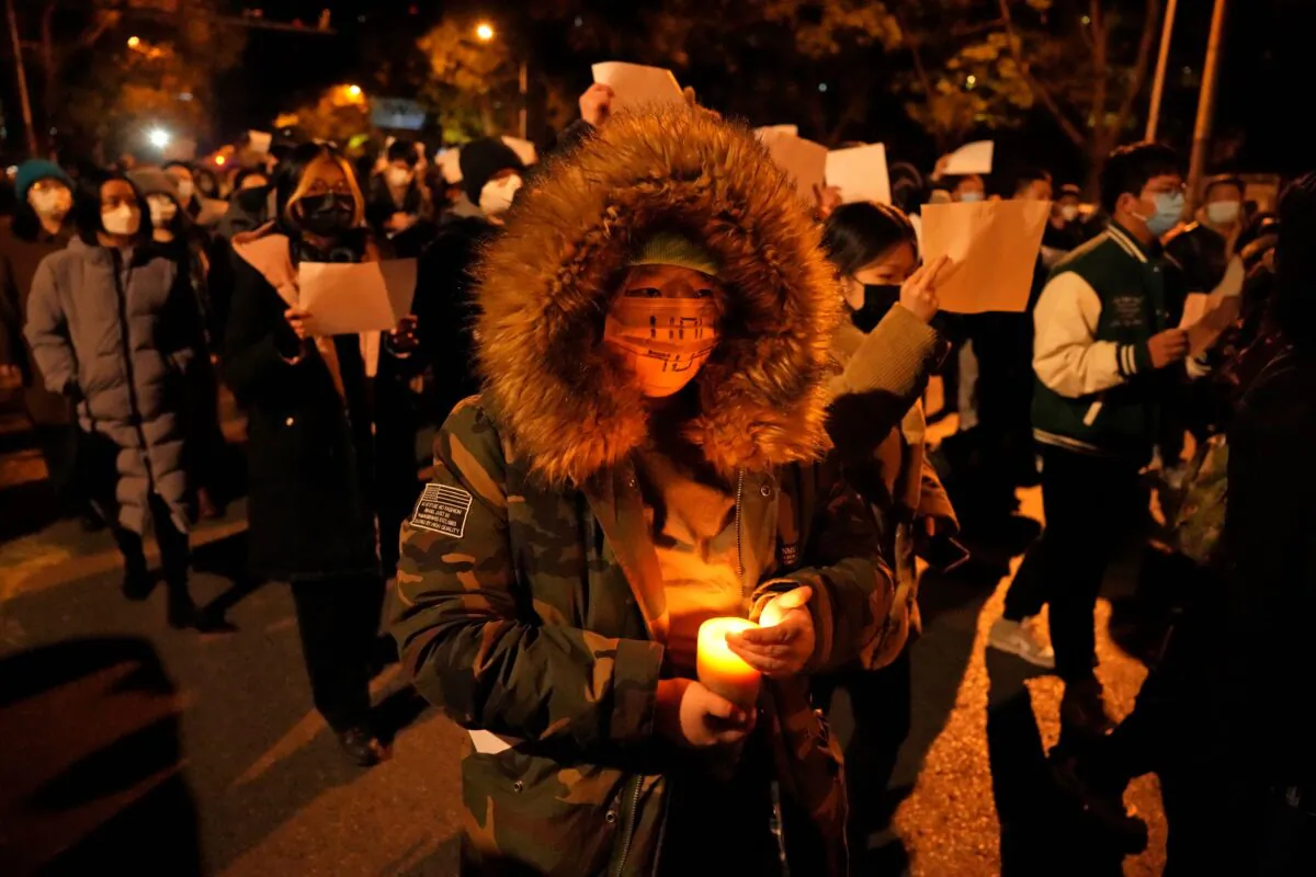 Protesters hold up blank papers and chant slogans as they march in protest against strict anti-virus measures in Beijing on Nov. 27, 2022. (Ng Han Guan/AP Photo)