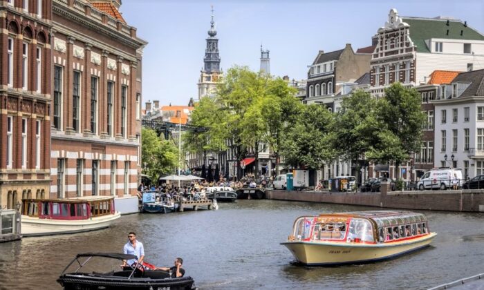 2022 年 6 月 17 日，乘客在荷兰阿姆斯特丹的一条运河上乘坐游船。（Remko De Waal/ANP/AFP via Getty Images）