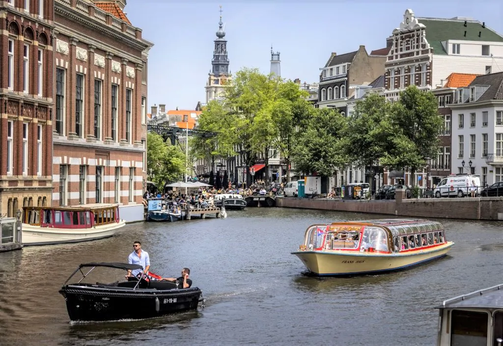 Passengers ride on a tour boat along a canal in Amsterdam in the Netherlands on June 17, 2022. (Remko De Waal/ANP/AFP via Getty Images)