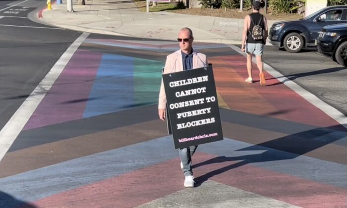 活动家克里斯·埃尔顿 (Chris Elton) 于 2022 年在加利福尼亚州西好莱坞举着写着“儿童不能同意使用青春期阻滞剂”的标语。（致谢 Billboard Chris）