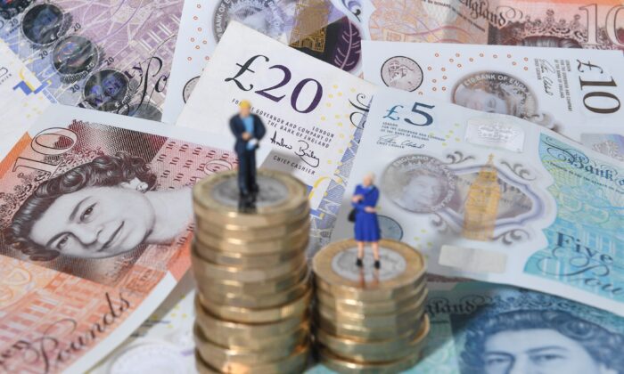 在这张日期为 2018 年 9 月 11 日的档案照片中，一男一女的模特站在一堆英国硬币和钞票上。（Joe Giddens/PA Media）