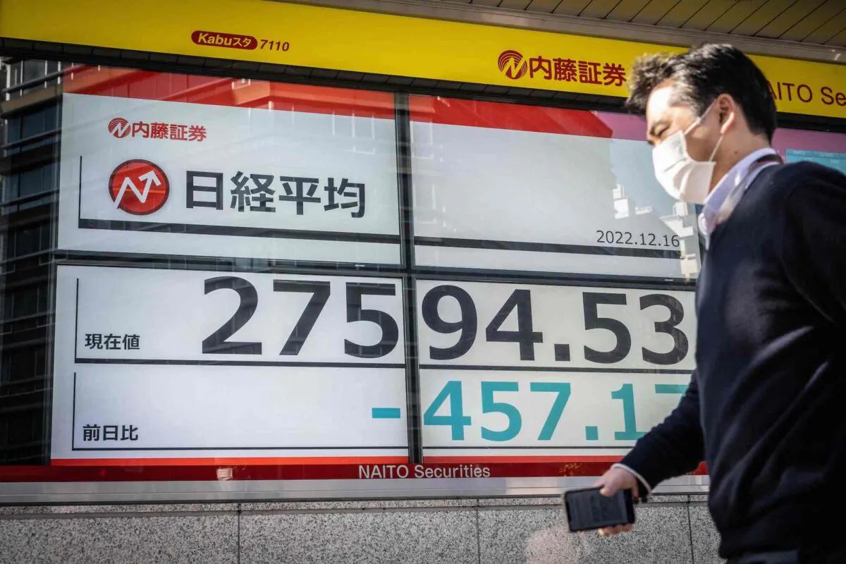 A man walks past an electronic board showing the numbers on the Tokyo Stock Exchange, along a street in Tokyo on Dec. 7, 2022. (Yuichi Yamazaki/AFP via Getty Images)