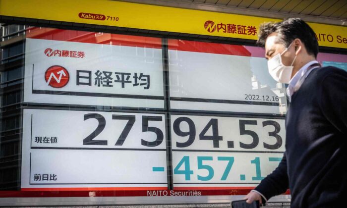 2022 年 12 月 7 日，一名男子在东京的一条街道上走过显示东京证券交易所数字的电子板。（Yuichi Yamazaki/AFP via Getty Images）