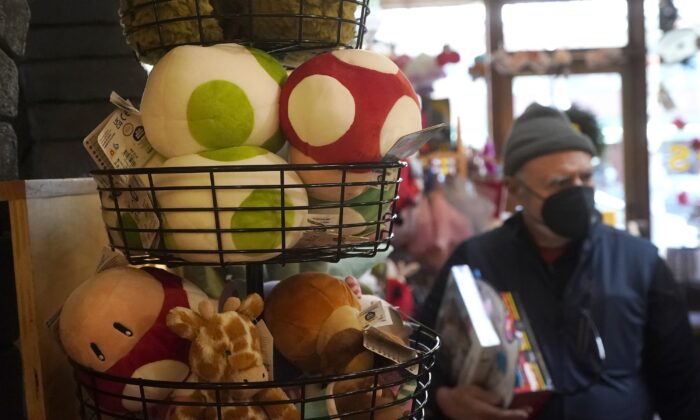 2022 年 12 月 12 日，顾客在加利福尼亚州伯克利的五只小猴子商店购物时展示了一篮毛绒蘑菇和动物。（Jeff Chiu/美联社照片）