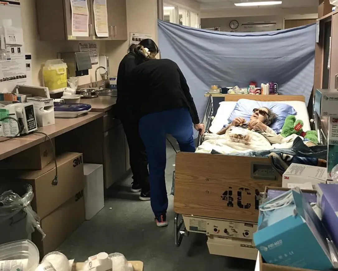 Irene MacNeill, 88, of Barnesville, N.B., lays in bed as nurses move the bed to access an electrical outlet after she was placed in a supply room at an over capacity Saint John Regional Hospital, in Saint John, N.B., in a Dec. 15, 2022, handout photo. (The Canadian Press/HO-Karen Totten)
