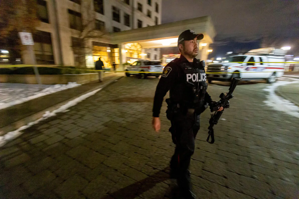 A police officer walks with a weapon after a fatal mass shooting at a condominium building in the Toronto suburb of Vaughan, Ont., on Dec. 19, 2022.  (Reuters/Carlos Osorio)