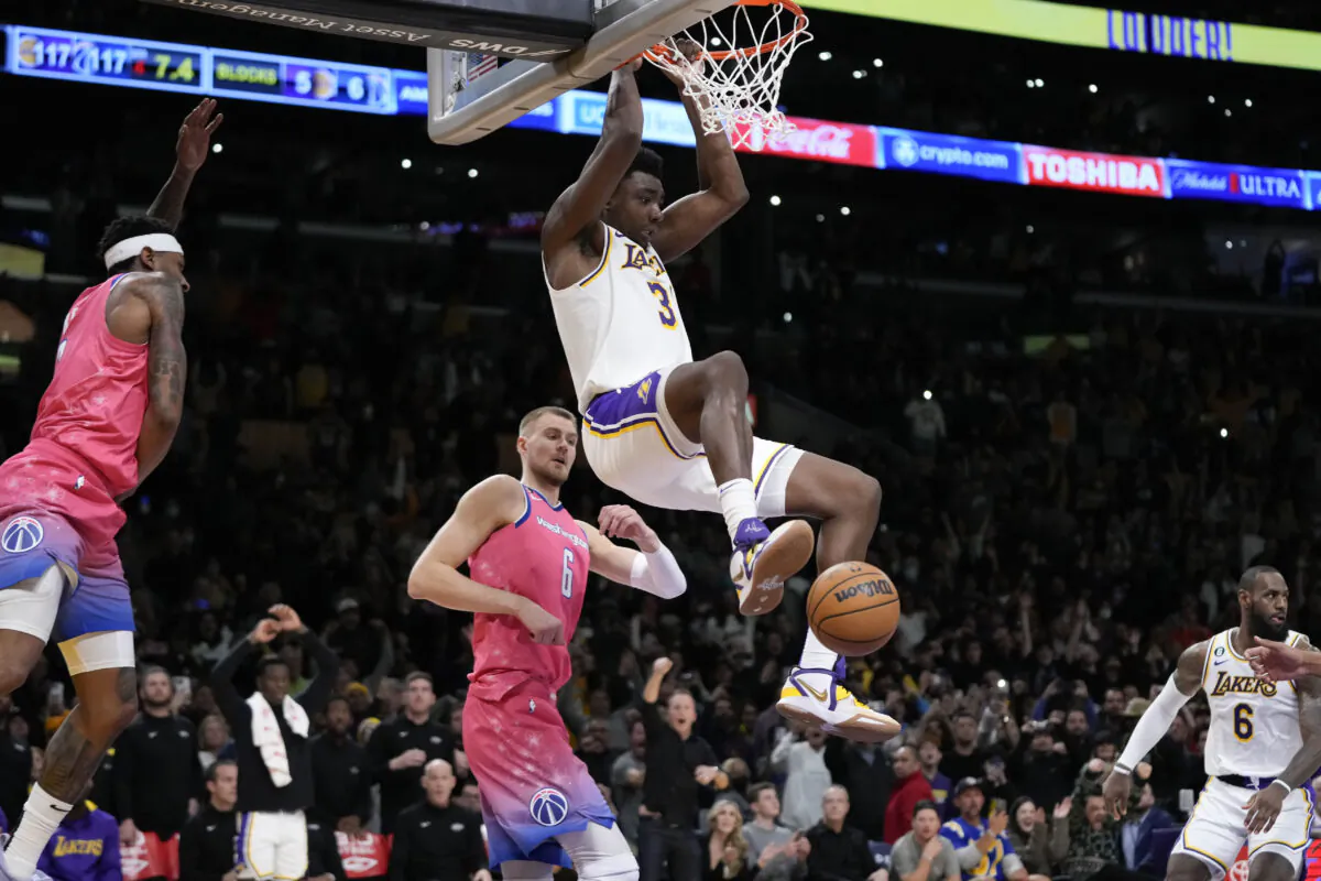 Los Angeles Lakers' Thomas Bryant (31) clings to the rim after dunking against the Washington Wizards during the second half of an NBA basketball game, in Los Angeles on Dec. 18, 2022. (Jae C. Hong/AP Photo)