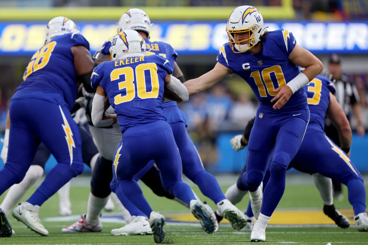 Justin Herbert (10) of the Los Angeles Chargers hands off the ball to Austin Ekeler (30) during the second quarter of the game against the Tennessee Titans at SoFi Stadium in Inglewood, Calif., on Dec. 18, 2022. (Harry How/Getty Images)
