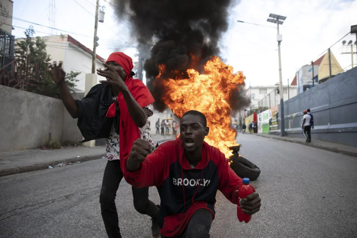 Protesters sing an anti-government song in front of a barricade of burning tires during a protest against the government in Port-au-Prince, Haiti, Nov. 18, 2022. (The Canadian Press/AP/Odelyn Joseph)