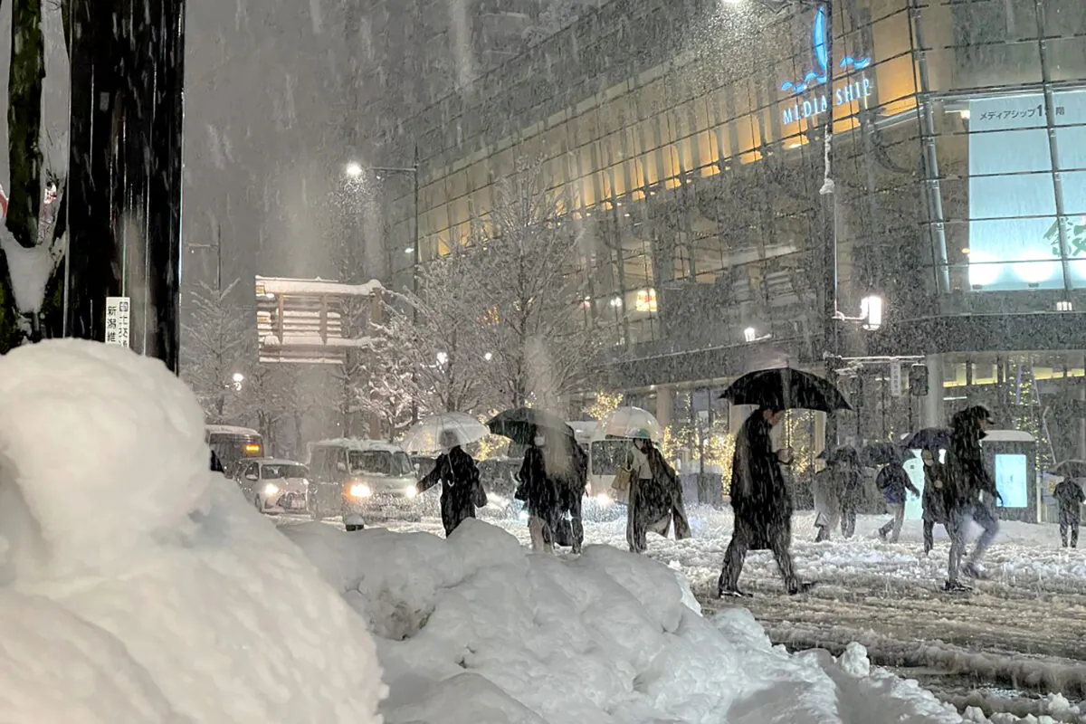 People cross the road carefully as heavy snow hits northern Japan in the city of Niigata, on Dec. 19, 2022. (STR/JIJI Press/AFP via Getty Images)