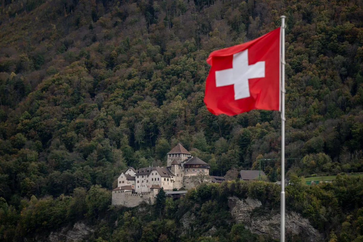 A Swiss national flag is foating next to the Vaduz Castle, the palace and official residence of the Prince of Liechtenstein, above Vaduz, at the border between Liechtenstein and Switzerland on Oct. 28, 2022. (Fabrice Coffrini/AFP via Getty Images)
