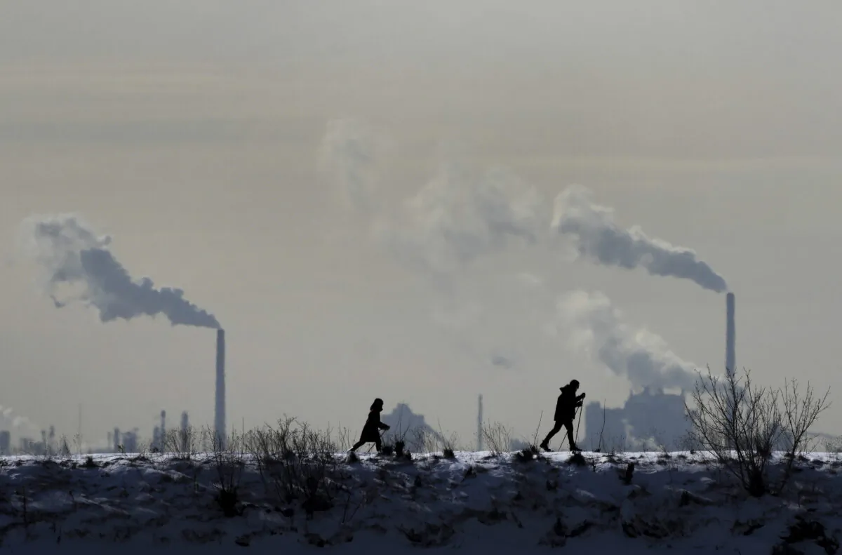 People cross-country ski in the cold weather as an industrial plant is shown in the background in Toronto on Feb. 4, 2022. (The Canadian Press/Nathan Denette)