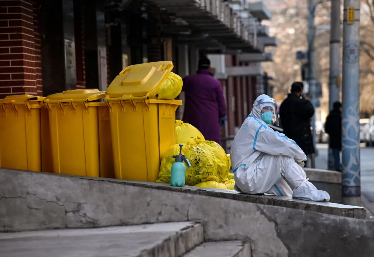 A worker wearing personal protective equipment sits next to waste material outside a fever clinic amid the COVID-19 pandemic in Beijing on Dec. 19, 2022. (Noel Celis/AFP via Getty Images)