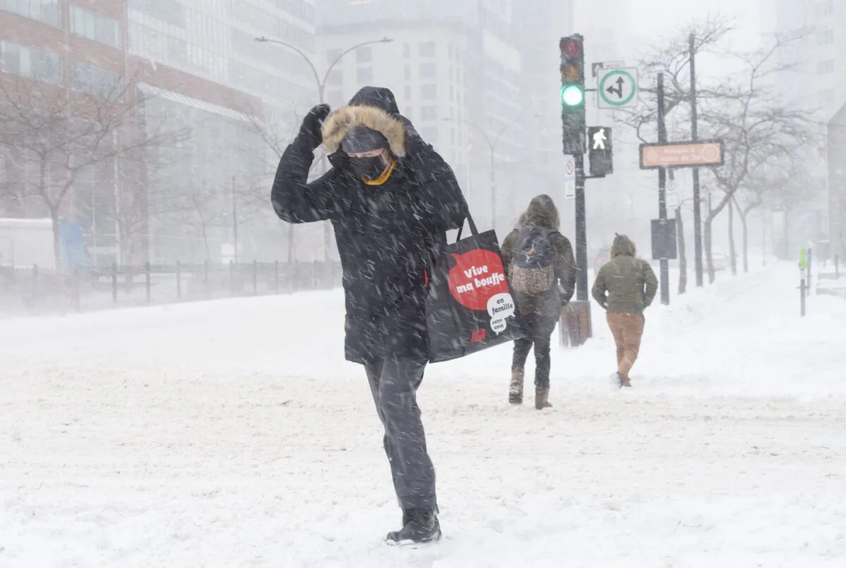 A woman crosses a near deserted street in downtown Montreal during a winter snowstorm on Jan. 17, 2022. (The Canadian Press/Paul Chiasson)