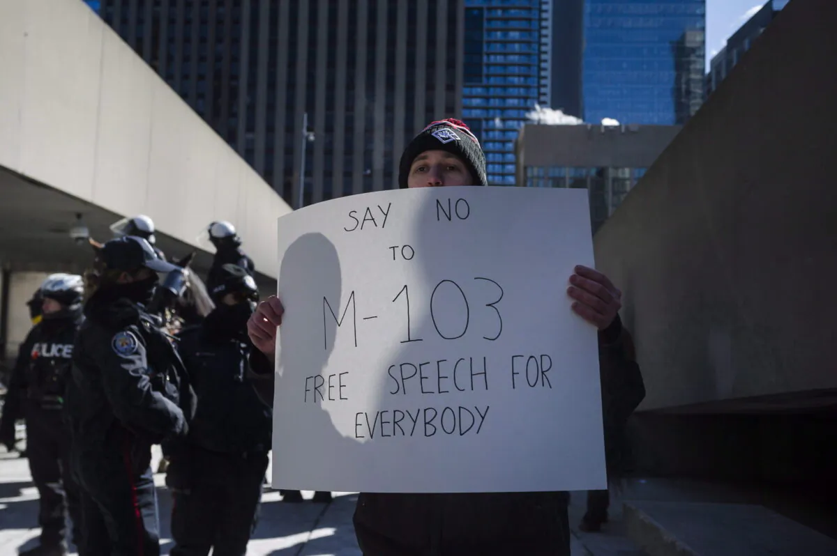 A protester holds a sign during a demonstration against the House of Commons motion M-103 at the Toronto City Hall on March 4, 2017. (The Canadian Press/Christopher Katsarov)