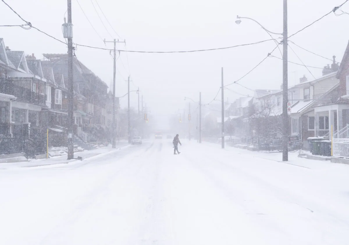 A man crosses a road during a snowstorm in Toronto on Dec. 23, 2022. (The Canadian Press/Arlyn McAdorey)