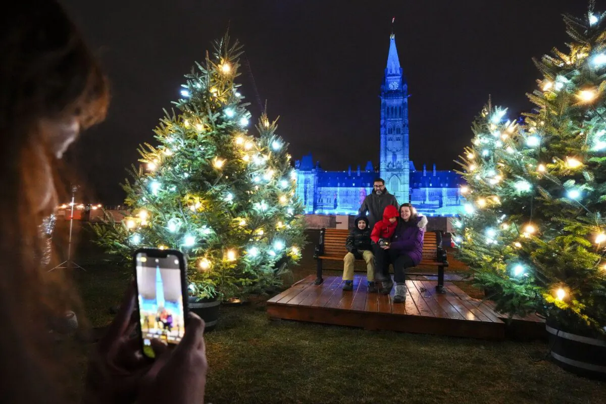 People take photos as the Peace Tower and Centre Block of Parliament Hill are lit with projections for Lights Across Canada in Ottawa on Dec. 7, 2022. (The Canadian Press/Sean Kilpatrick)
