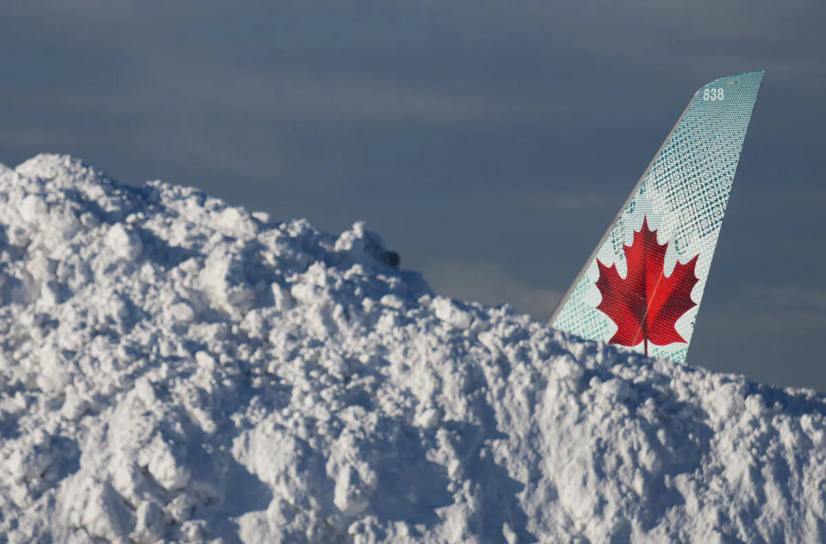 The tail of an Air Canada aircraft is seen behind a pile of snow at Vancouver International Airport in Richmond, B.C., on Dec. 21, 2022. (Darryl Dyck/The Canadian Press)