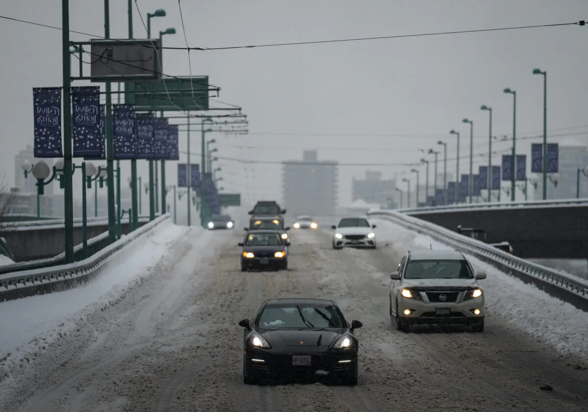 Motorists travel on the snow-covered Cambie Bridge as freezing rain falls in Vancouver on Dec. 23, 2022. (The Canadian Press/Darryl Dyck)