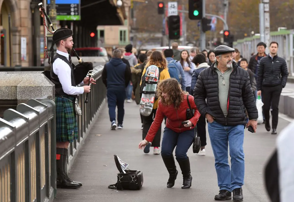 A woman gives money to a busker playing the bagpipes in Melbourne's central business district on July 2, 2019. (William West/AFP via Getty Images)