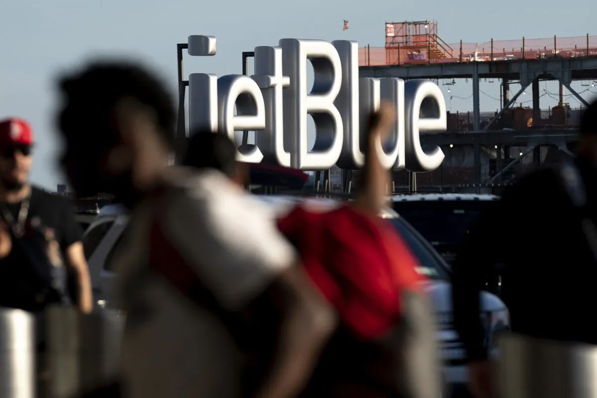 Travelers make their way near a JetBlue sign ahead of the Fourth of July holiday weekend at John F. Kennedy International Airport in New York on June 28, 2022. (Julia Nikhinson/AP Photo)
