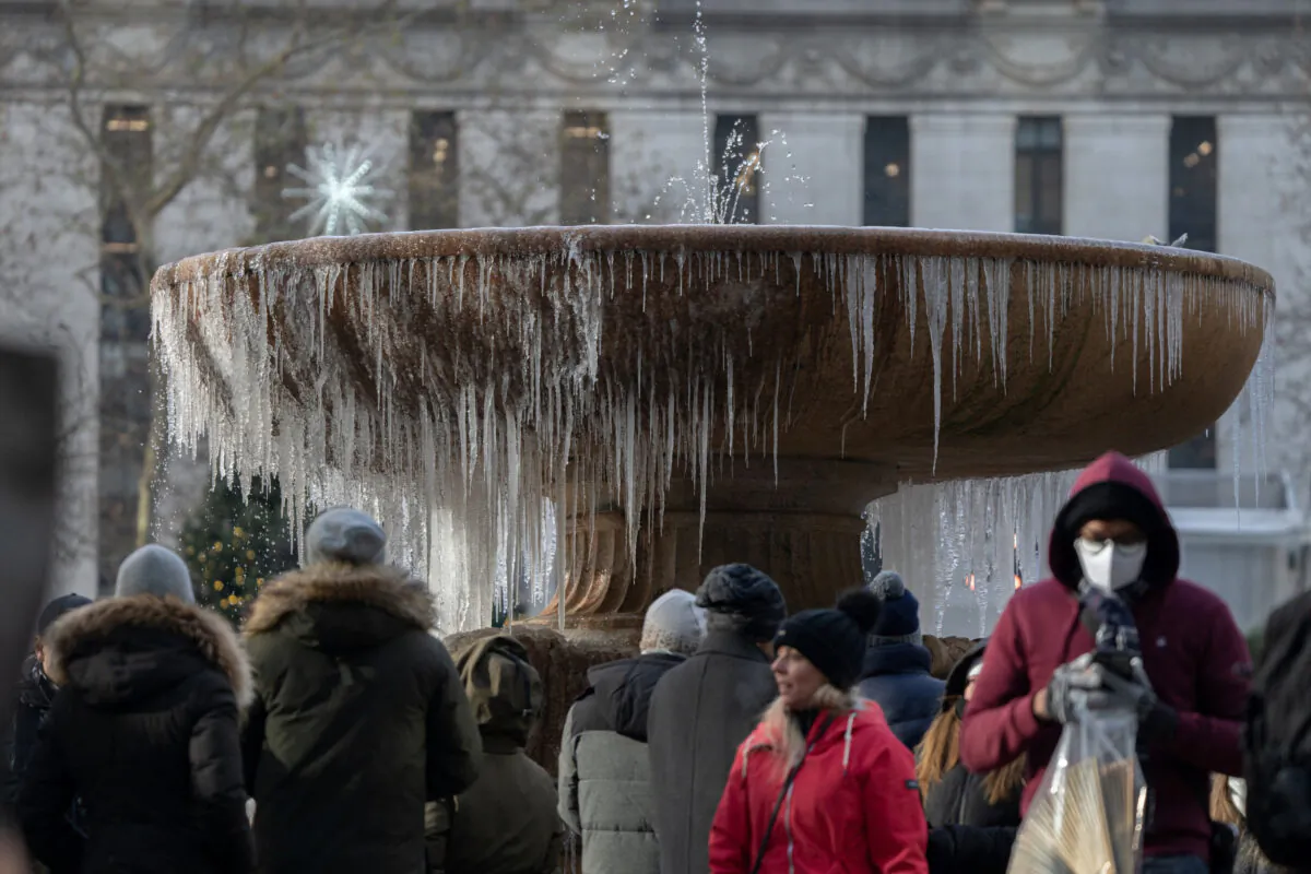 People stand in front of a mostly frozen Bryant Park fountain on Christmas Eve in Manhattan, New York, on Dec. 24, 2022. (Jeenah Moon/Reuters)