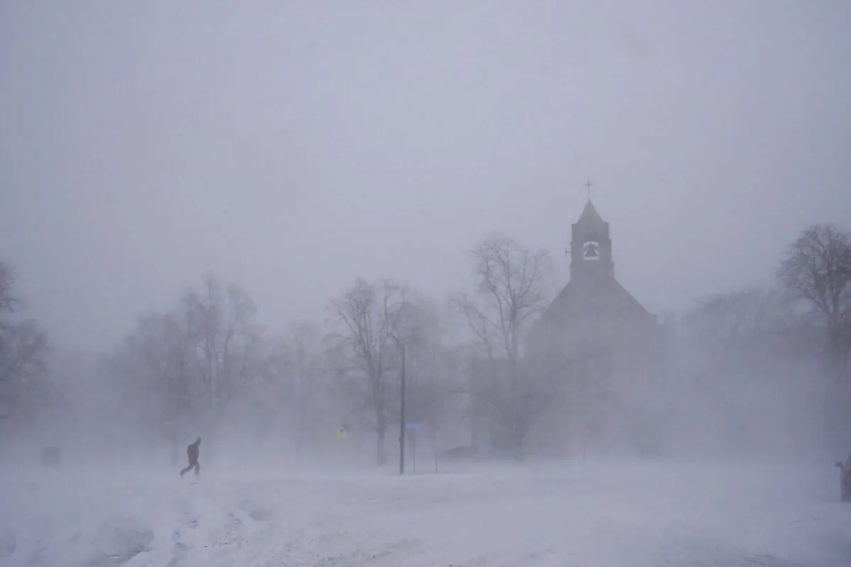 A lone pedestrian in snow shoes makes his way across Colonial Circle as St. John's Grace Episcopal Church rises above the blowing snow amid blizzard conditions in Buffalo, N.Y. on Dec. 24, 2022. (Derek Gee/The Buffalo News via AP)
